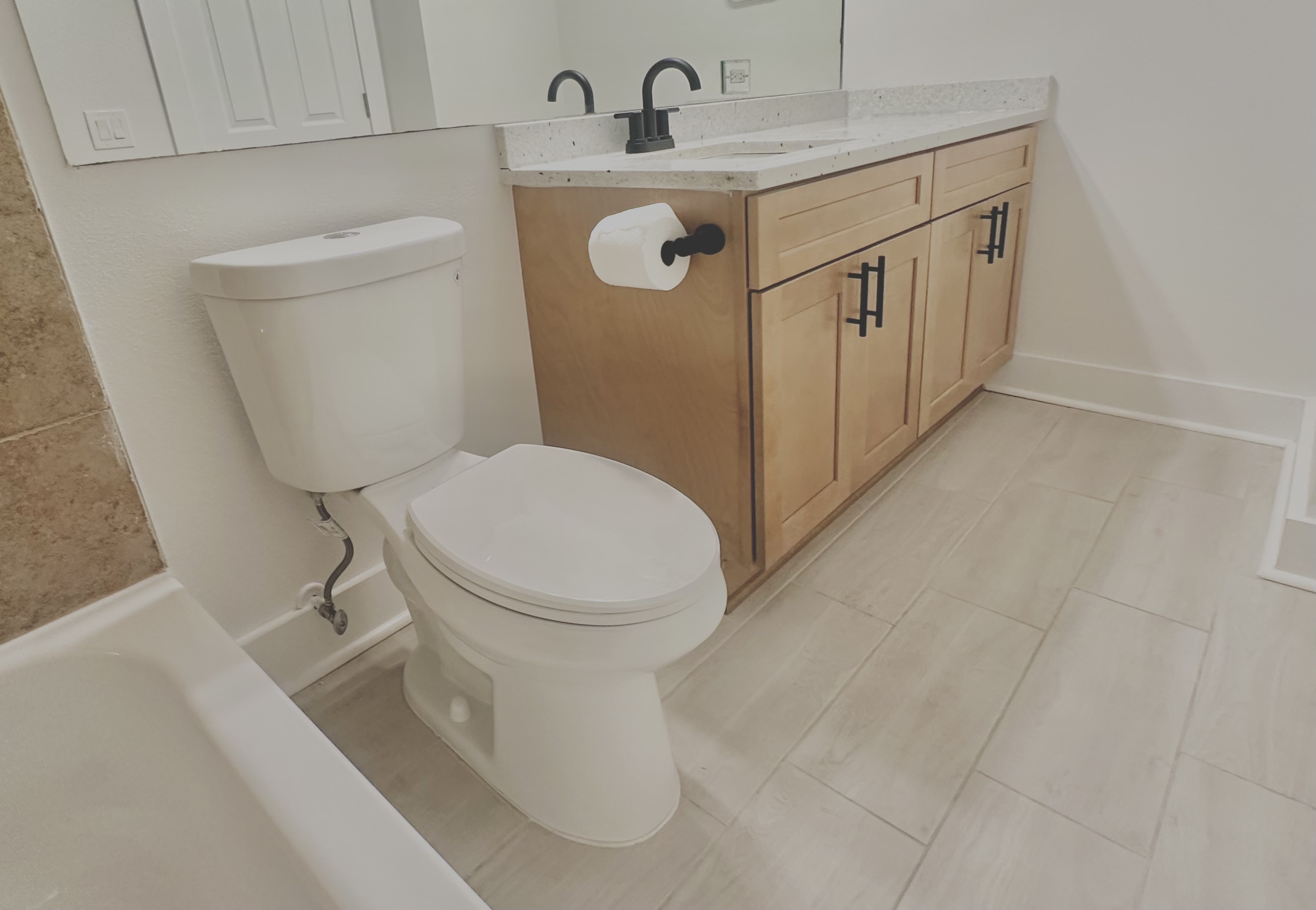 Renovated bathroom with wood vanity and matte-black hardware